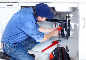 Mature plumber fixing a sink at kitchen